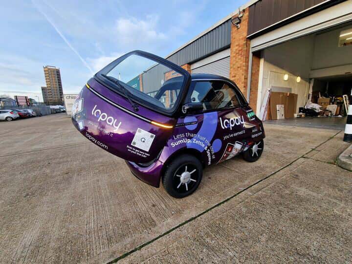 An image of the back left corner of the Lopay car showing the vehicle graphics and wraps with the trunk open
